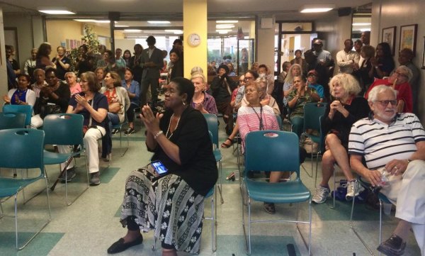 About RIOC's Special Friendship with the RI Seniors Association CBN/RI Senior Center First Anniversary Celebration. A crowd overflowing with satisfied seniors applauds.